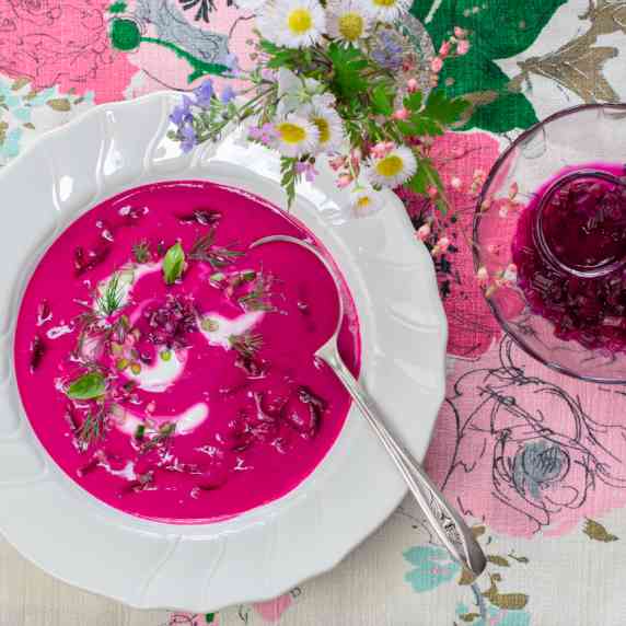 Cold Beet & Kefir Soup in vintage bowl garnished with herbs and pickled beet stems. 