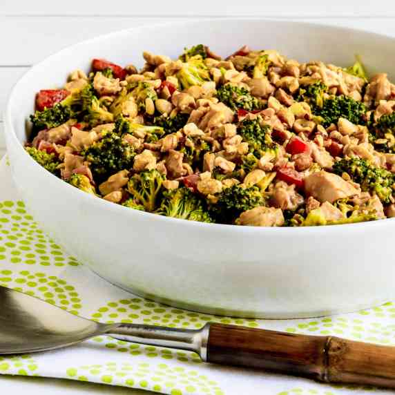 Chicken Broccoli Salad in serving bowl on green white napkin, with serving spoon.