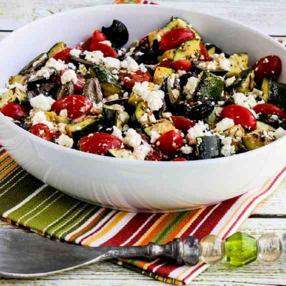 Grilled Zucchini Greek Salad in serving bowl on striped napkin.