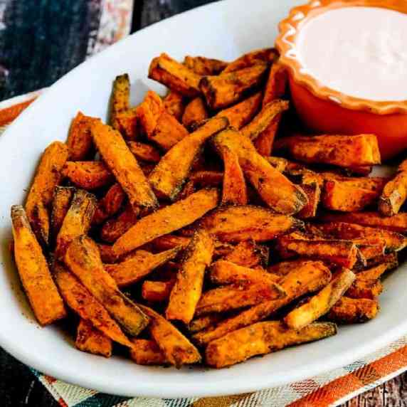 Air Fryer Sweet Potato Fries shown on serving platter with Sriracha Aioli Dipping Sauce in bowl.