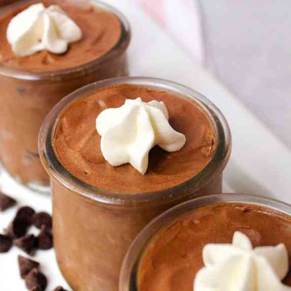 chocolate mousse in small jars topped with whipped cream