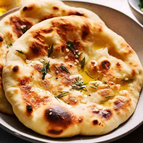 Naan breads on a white plate drizzled with olive oil.