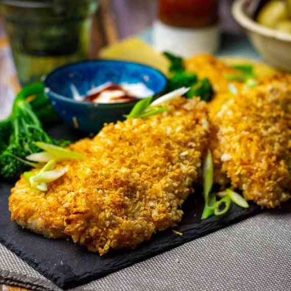 flat pieces of panko crusted chicken on a black slate board. 