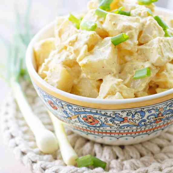 Zingy potato salad topped with spring onions in a fancy bowl