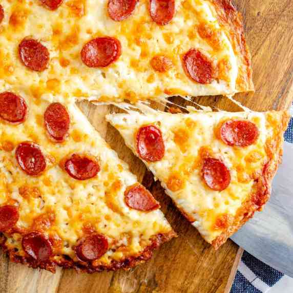 Chicken crust pizza cheese pull slice on a wooden board