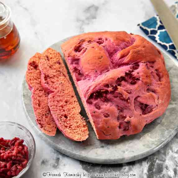 Sliced loaf of pink challah on a marble platter.