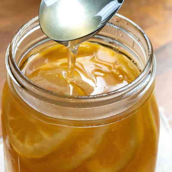 A table spoon of homemade apple-lemon syrup being poured into the mason jar