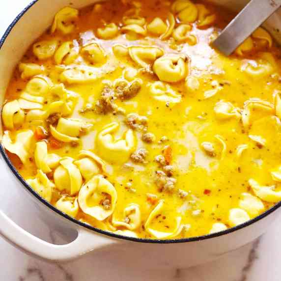 sausage tortellini soup in pot with ladle