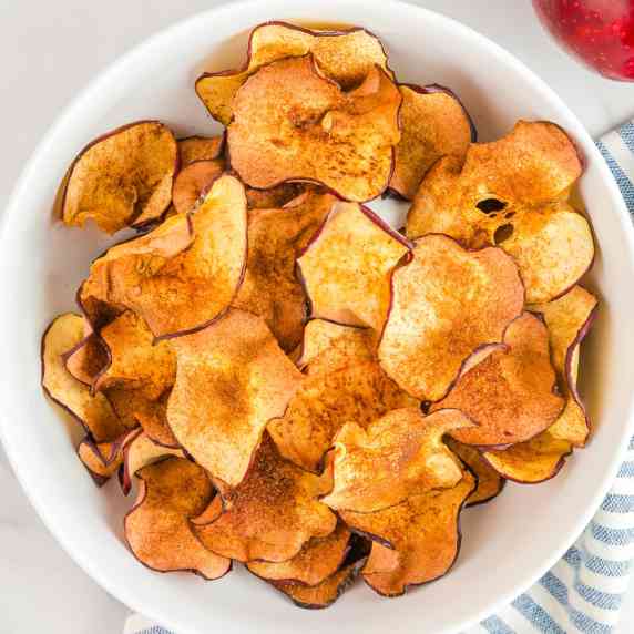 Close up square view of apple chips in a bowl.