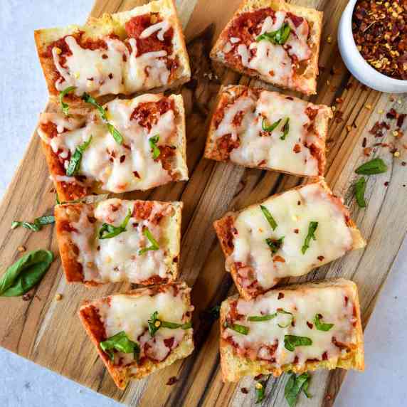 Air fryer french bread pizza cut into piece on a cutting board.