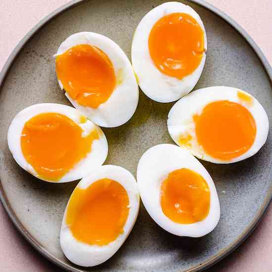 Six halved soft boiled eggs on a gray stoneware plate