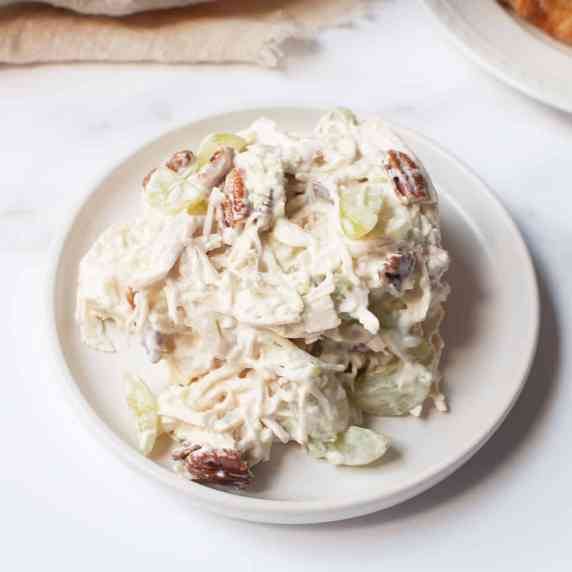 Chicken salad with pecans and grapes on a white plate.