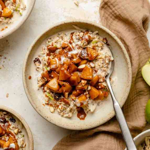 Apple cinnamon overnight oats served in a bowl with apple cinnamon topping on top and a spoon.