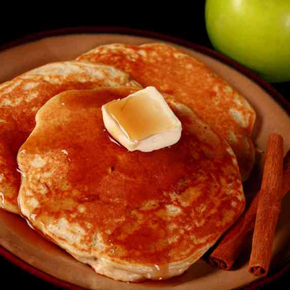 A plate of apple cinnamon protein pancakes topped with maple syrup.