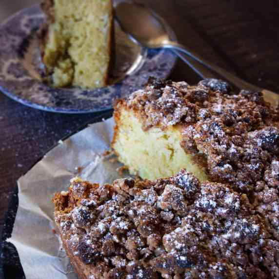 a apple and olive oil cake sits with a slice cut. 
