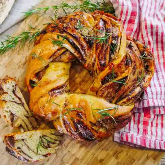Rosemary, Olive & Blue Cheese Bread crown served on rustic wooden chopping board with garnish