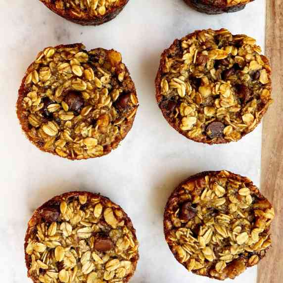 banana walnut chocolate chip baked oatmeal in muffin size on a marble cutting board