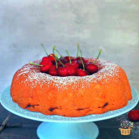 Cherry Jam Basque Cake with cherries in the middle on a blue cake stand