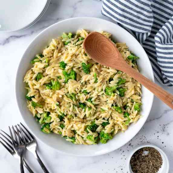 Broccoli cheddar orzo in a white serving bowl.