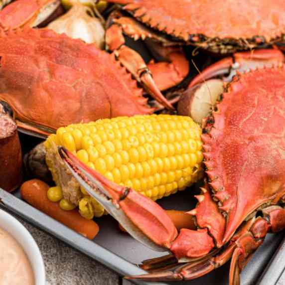 boiled crabs with corn, carrots and garlic and smoked sausage with a bowl of dip