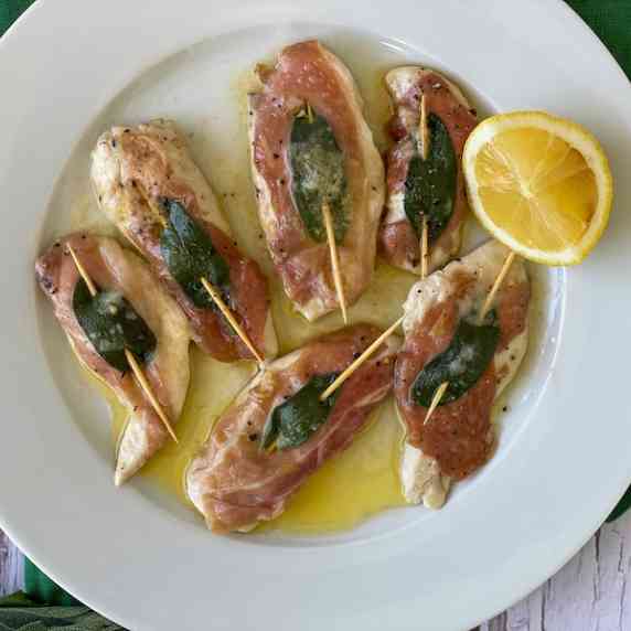 Chicken tenders with ham and sage on a white plate