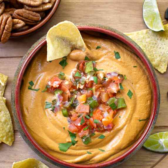 Spicy vegan queso in a bowl with tortilla chips
