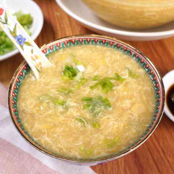 Corn Egg Drop Soup in a bowl with a spoon on a wooden table