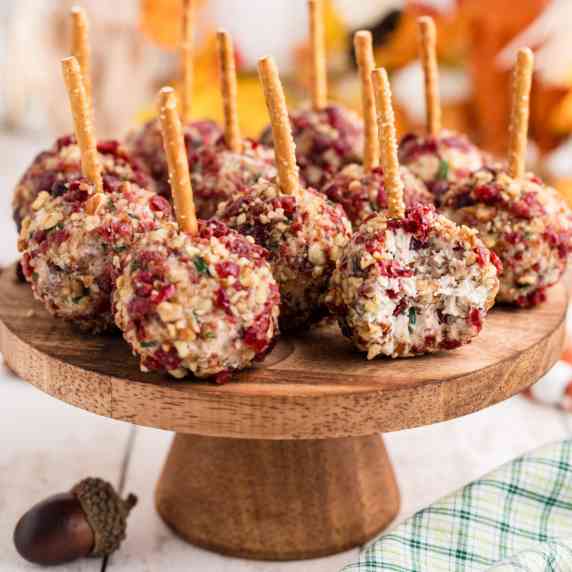 Small cake stand full of cranberry pecan cheese ball bites, with one having a bite missing.
