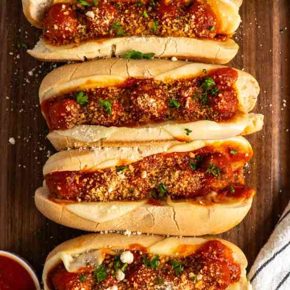 Meatball subs on a wood cutting board.