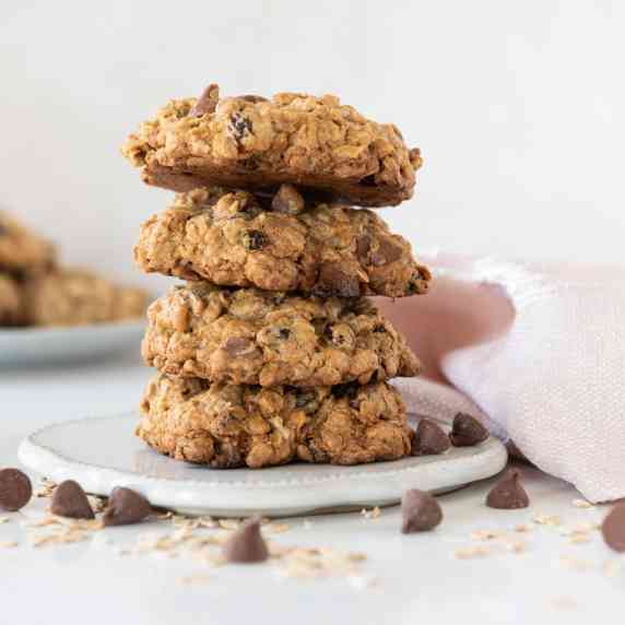 Stack of Gluten Free Oatmeal Chocolate Chip Cookies on a white plate with a pink napkin