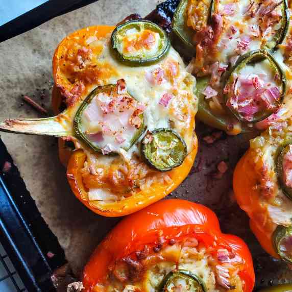 Cheesy stuffed peppers on a parchment lined baking sheet.