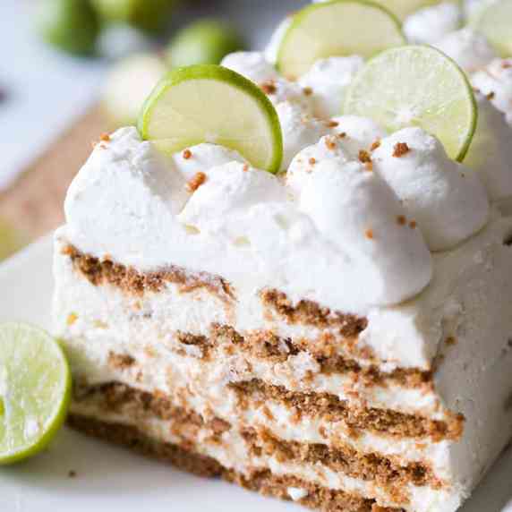 A layered icebox cake topped with lime slices on a white platter.