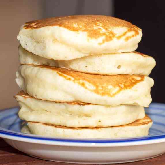 A stack of five super thick and fluffy pancakes on a blue plate.