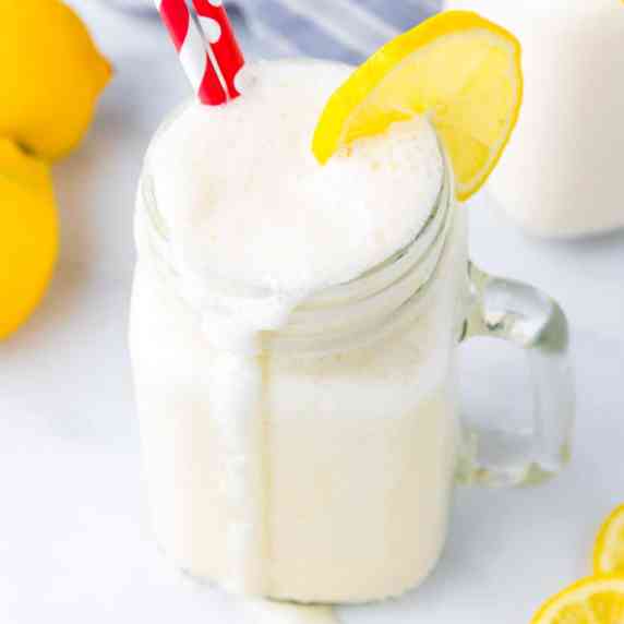 Close up overhead view of a frosted lemonade with a lemon slice and red straws.