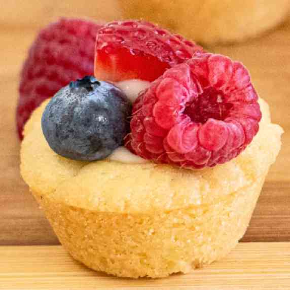 Close up of a cookie cup filled with cream cheese and topped with fruit on a platter.