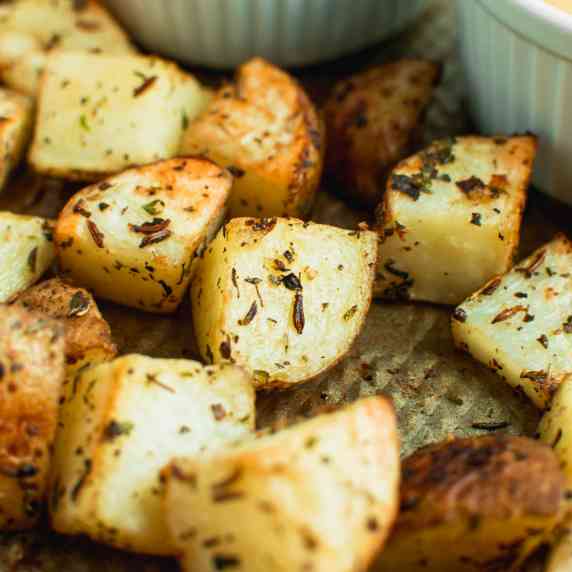 close up of crispy roasted garlic herb potatoes on a baking sheet.