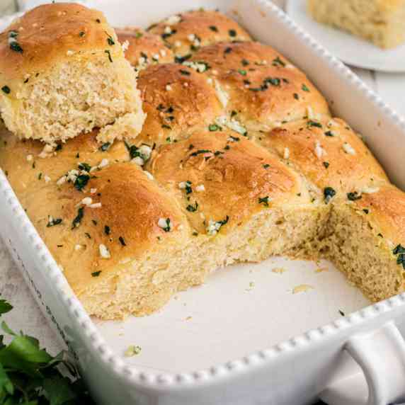 Close up of a dish with garlic butter rolls with parsley.