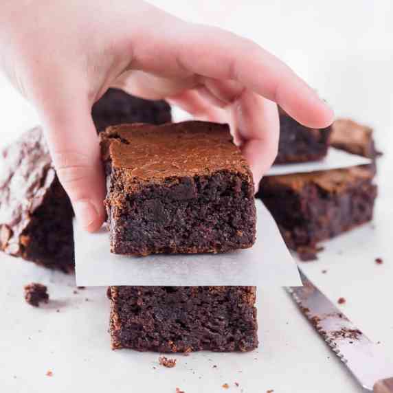 Stack of 2 brownies, with hand grabbing top piece.