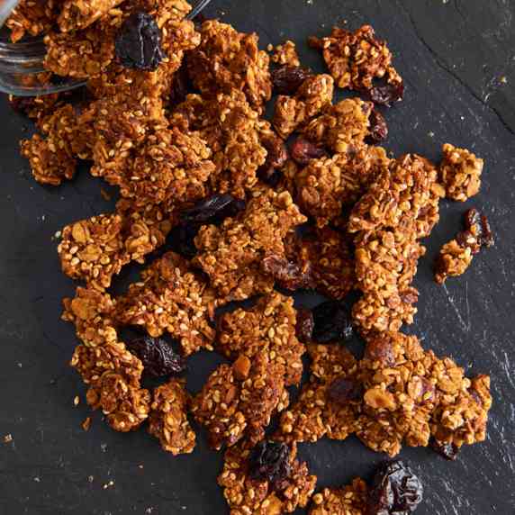 Malted Crunchy Granola Clusters, tumbling out of a jar onto black slate
