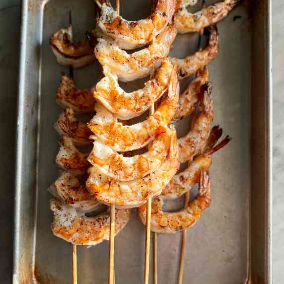 Grilled shrimp kabobs on skewers in a pan