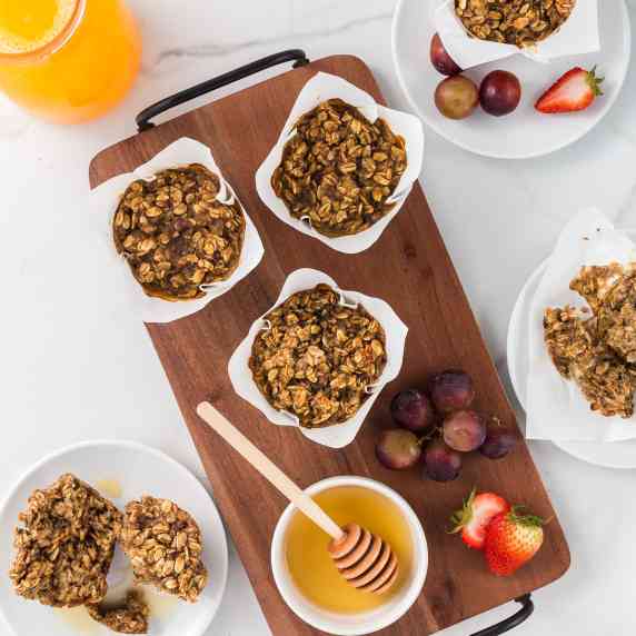 banana oatmeal muffins on a serving board with honey and fruit served with orange juice