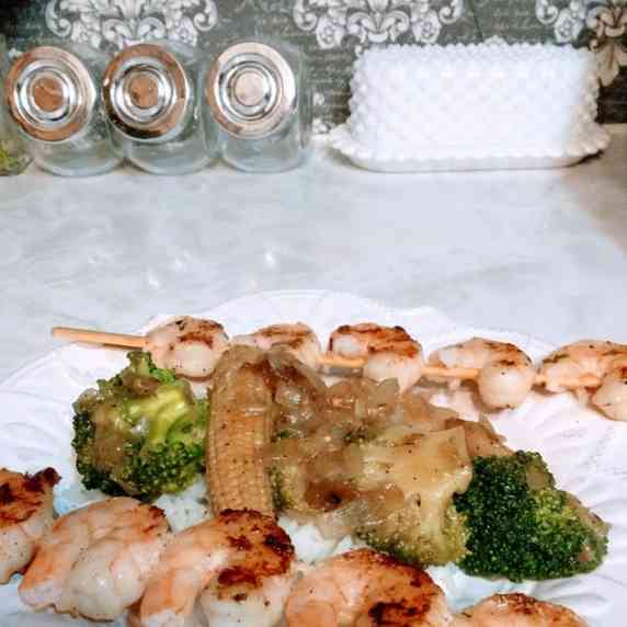Grilled shrimp with vegetables and rice plated on vintage white scalloped dish on top of counter