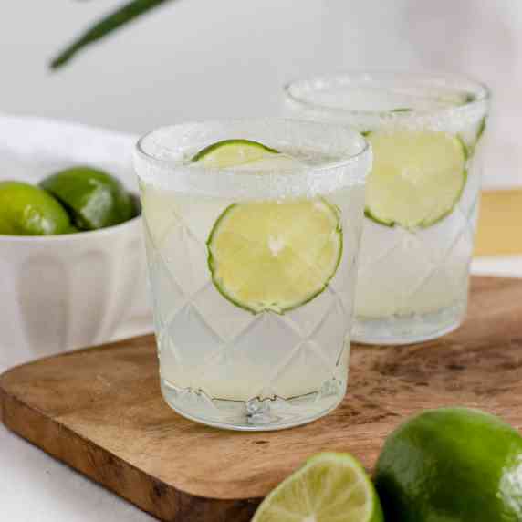 two tequila cocktails with lime slices 
