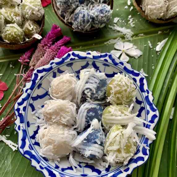 Thai coconut balls in three colors, topped with shredded coconut flakes.