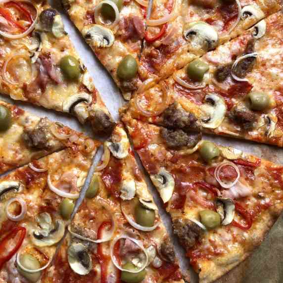 Just-baked and sliced whole wheat thin crust pizza with meat and vegetables.