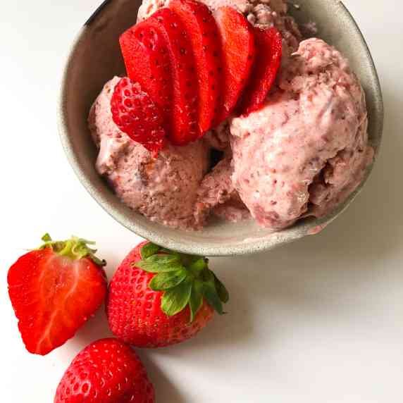 Strawberry Ice Cream in a bowl, topped and surround by Strawberries 