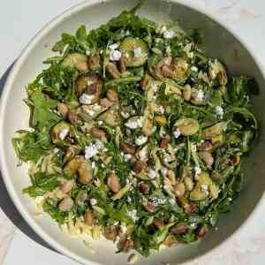 Arugula topped with lemony orzo, toasted pistachios, sautéed zucchini, feta, dill, and white beans