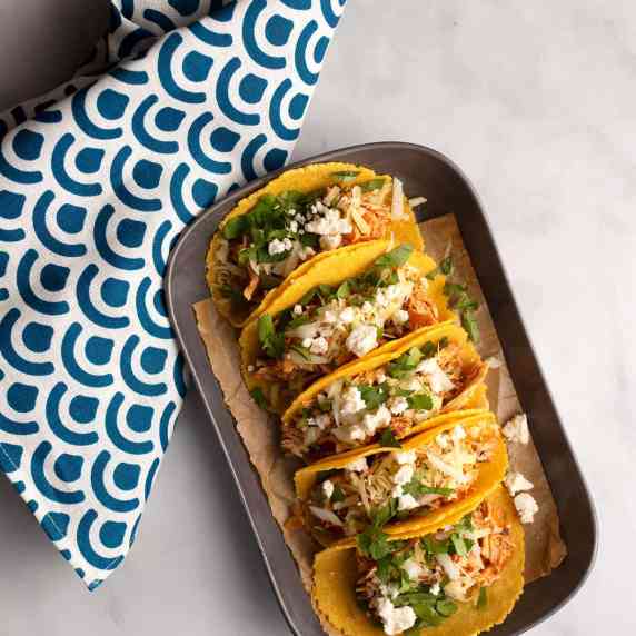 Five Chicken Tinga Tacos lined up on a pewter platter
