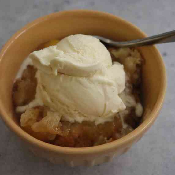 Bowl of Peach Cobbler with a scoop of vanilla ice cream.