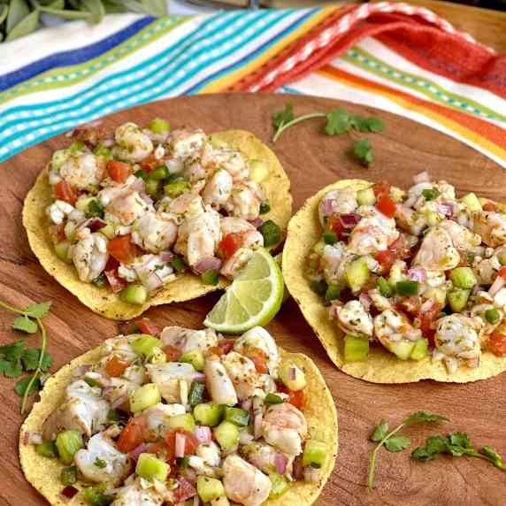 Refreshing ceviche placed on top of crunchy tostadas sitting on a wooden cutting board